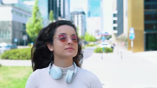 Woman Walking with Books and Headphones in City