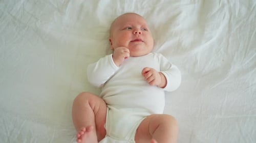 Cute Infant Relaxing on a White Bed