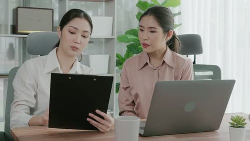 Two young enthusiastic businesswoman working together in the office workspace.