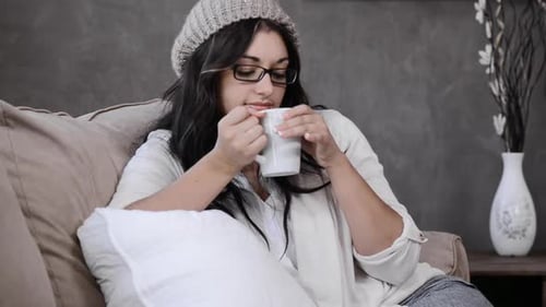 Attractive brunette woman enjoys morning coffee and sunlight in her luxury apartment