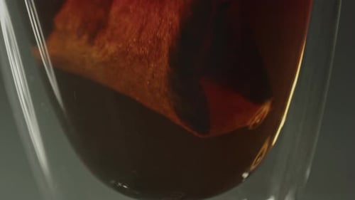 Extreme Nahaufnahme eines Teebeutels, der auf und ab gezogen wird, um heißes Wasser in ein Glas zu gießen.