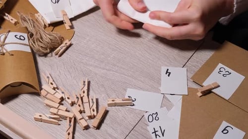 Unrecognizable Young Woman Sticks Number on Craft Bag Fastens with Clothespin