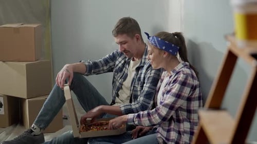 Young Couple Eating Pizza in New Home