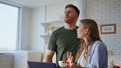Couple Smiling and Looking at Laptop Together in Kitchen