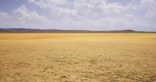 Dry Desert Landscape Under a Bright Sky Filled with Fluffy Clouds