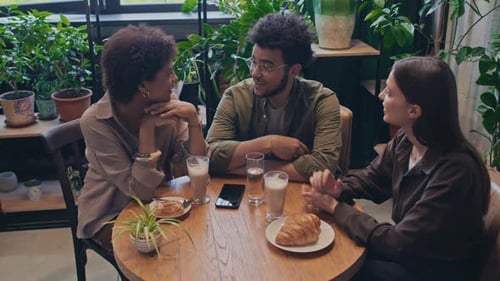 Three Multiracial Friends Chatting while Drinking Coffee in Restaurant