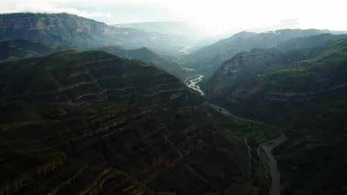Dappled Light on Mountainous River Valley Rays of Light Spotlight a Snaking River Amidst Layered