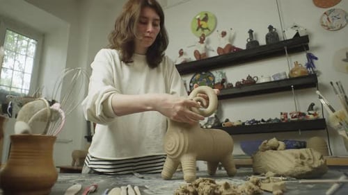 Young Woman Shaping Clay Ram in Studio
