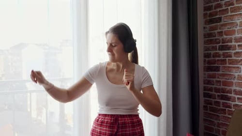 Woman Dancing with Headphones in Bright Room