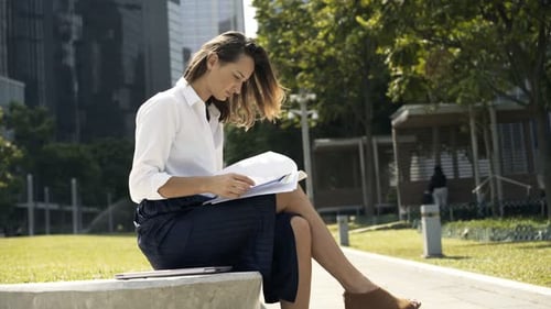 Young Businesswoman Analyzing Documents in City Park