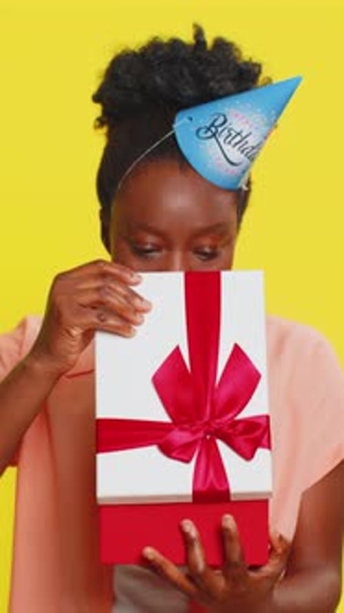 African American Woman Opening Present Gift Box Party Hat Birthday Surprise Joyful Reaction