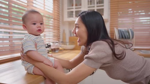Loving Woman Interacts with Baby in Bright Kitchen