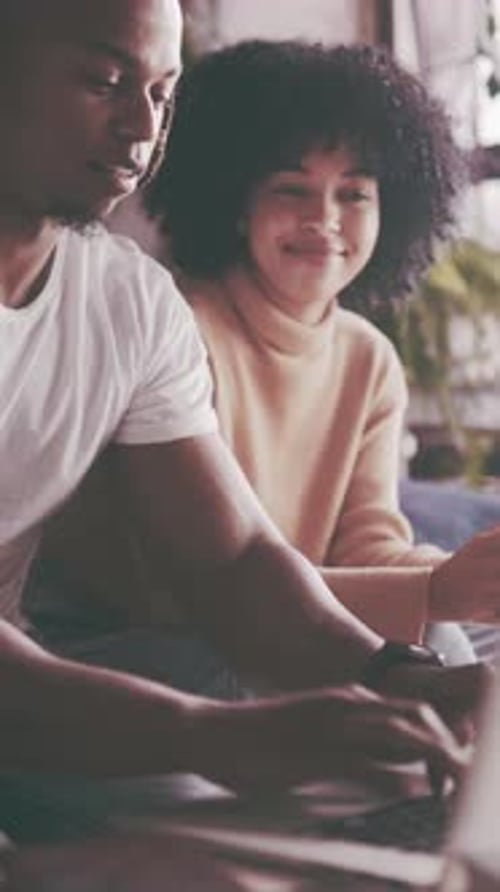Man and woman sitting using a laptop inside