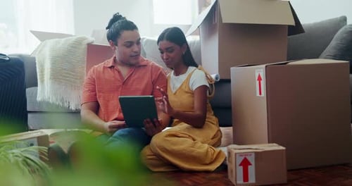 Young Couple Using Tablet Surrounded by Boxes