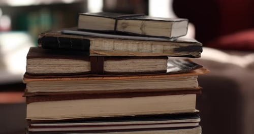 Handheld close-up shot of stack of old notebooks on coffee table