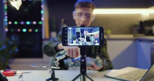 Concéntrese en la pantalla del teléfono inteligente. Un joven está transmitiendo en vivo un blog de capacitación sobre Computer Motherboar