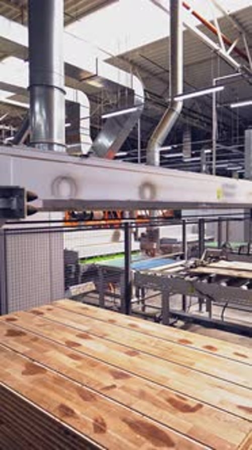 Special automatic equipment shifts wooden boards on a pallet in the workshop.