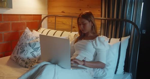 Young Woman Working on Laptop in Bedroom
