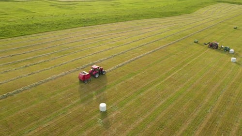 Traktor mit runder Heuballenpresse entladen und ernten Heuballen von landwirtschaftlichen Maschinen auf dem Feld