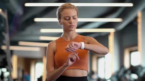 Closeup Thoughtful Fitness Woman Using Smartwatch at Gym. Portrait of Surprised Sportswoman