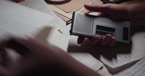 Vue de dessus d'une main tenant un magnétophone et une lettre manuscrite