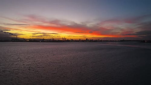 Dramatic Sunset Over Port Cranes on Water