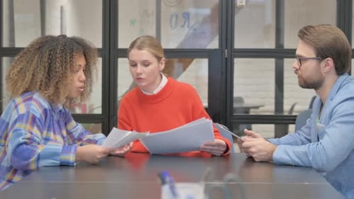 Collaborative Team Discussing Documents in Modern Office