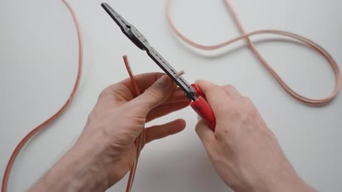 Hands Cutting Wire with Wire Stripper Tool
