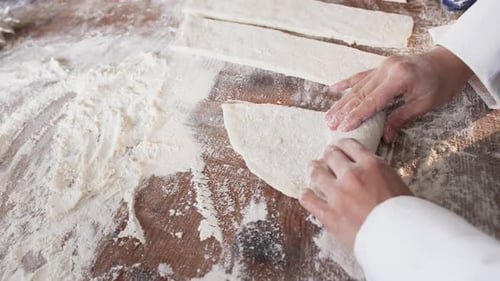 Asiatische Bäckerin arbeitet in der Backküche und rollt Teig in Zeitlupe auf der Theke