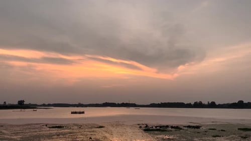 The golden sun dips below the horizon, casting a warm glow over the serene sunset lake.