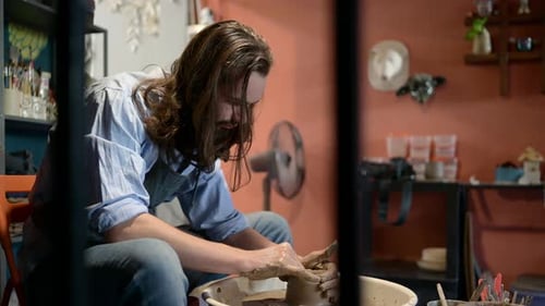 Man Shaping Clay on Pottery Wheel in Studio