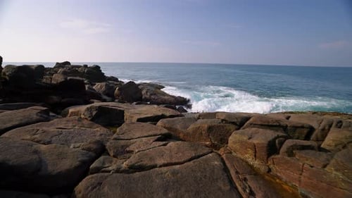 Crashing Waves Surge Against Rugged Rocks at Shoreline Seascape Ocean View with Dynamic White Foam