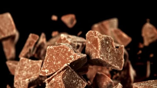 Chocolate chunks falling in slow motion against black background