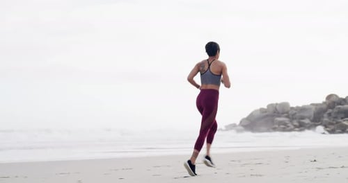 4k video footage of an attractive young sportswoman running on the beach