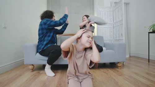 Distressed Girl Covering Ears During Parental Conflict at Home