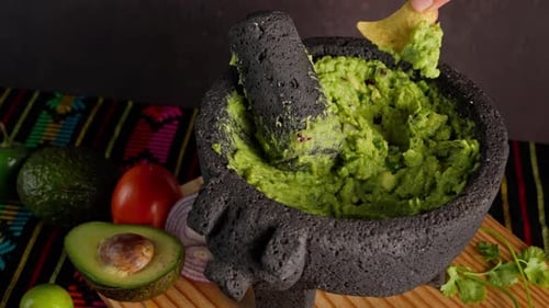 Mexican Guacamole, A Mexican Woman Spreads Guacamole On A Tortilla Chips, Guacamole On A Molcajete