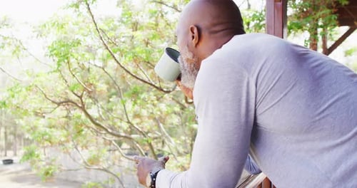Adult Man Drinking Coffee on Porch Overlooking Nature