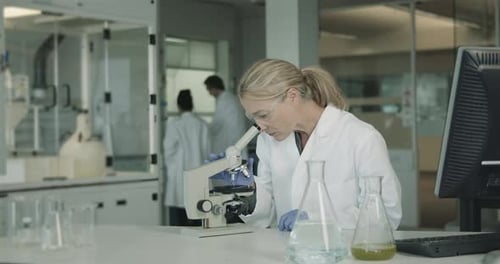 Woman Using Microscope in Laboratory Setting