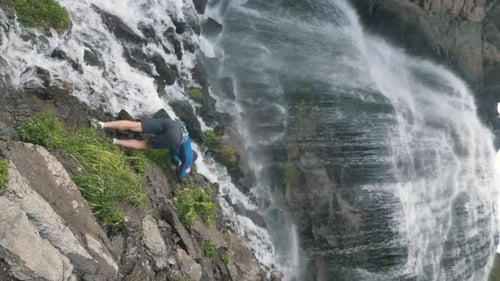 Adventurer Standing by Rocky Cliff Waterfall