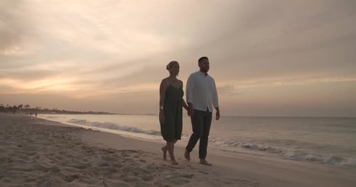 Romantic caribbean honeymoon sunset beach walk with couple holding hands