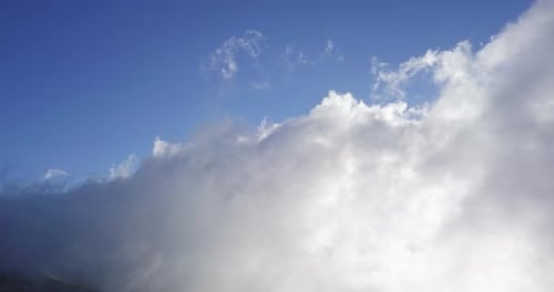 Wide view of clouds moving over the slopes of a mountain on a sunny day. Maui, Hawaii.