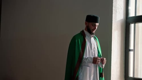 Silhouette eines arabischen Priesters, der in nationaler Kleidung in einer Moschee steht und mit Hilfe zu Allah betet