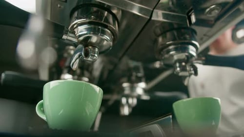 Pouring coffee flows from the machine into the cup making hot drink using the filter holder freshly