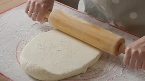 Rolling dough with rolling pin on kitchen counter