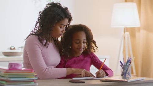 Woman Helping a Girl with Schoolwork in Home