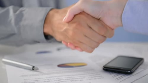 Profissionais de negócios apertam as mãos em prédio de escritórios após fechar negócio bem-sucedido