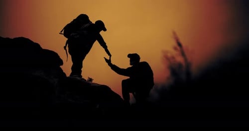 Silhouetted Hikers Helping Each Other At Sunset