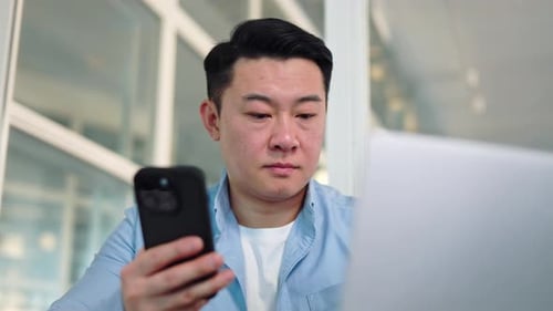 Young Adult Using Smartphone and Laptop in Office