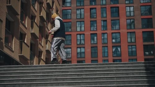A Young Man in Casual Streetwear Performs Energetic Movements in an Urban Setting with Highrise