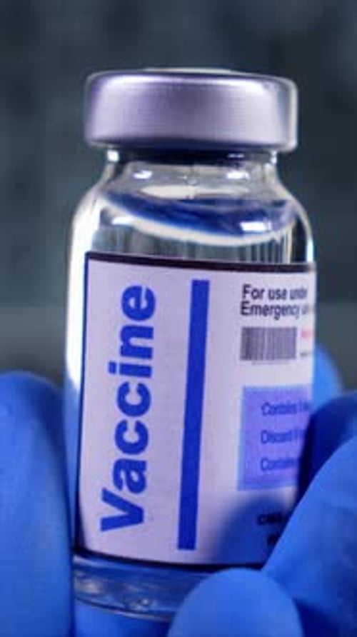 Vial of Vaccine Held by Blue-Gloved Hand